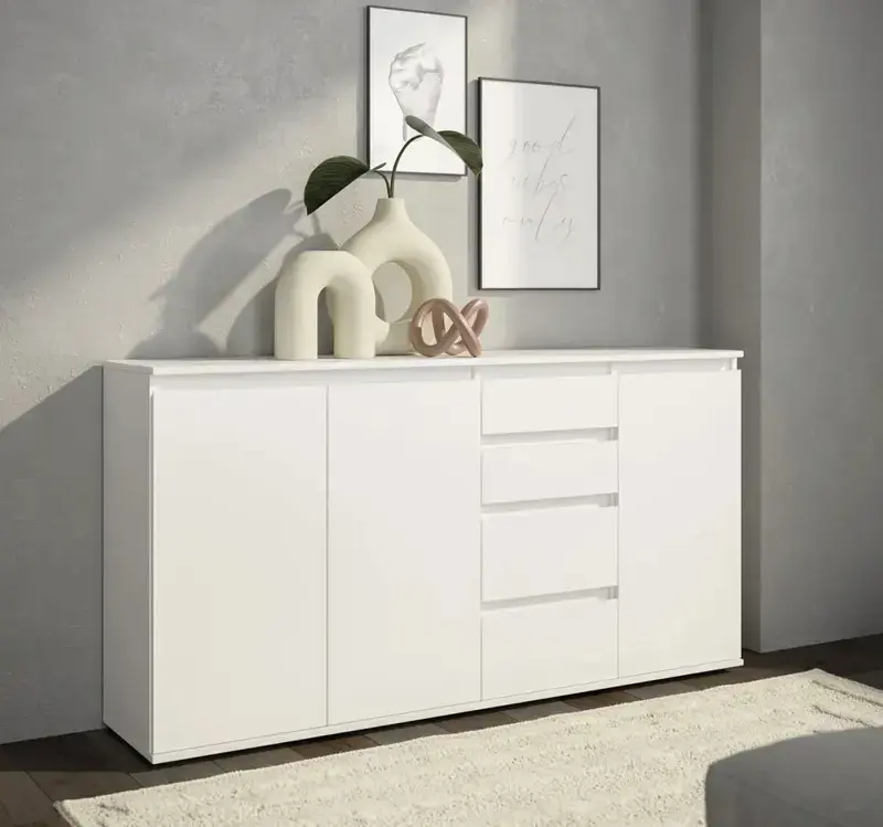 Weisses Sideboard mit Türen und Schubladen vor grauer Wand, darauf helle Keramikvasen mit Zweig, Skulptur und zwei gerahmte Bilder, vorn heller Teppich.